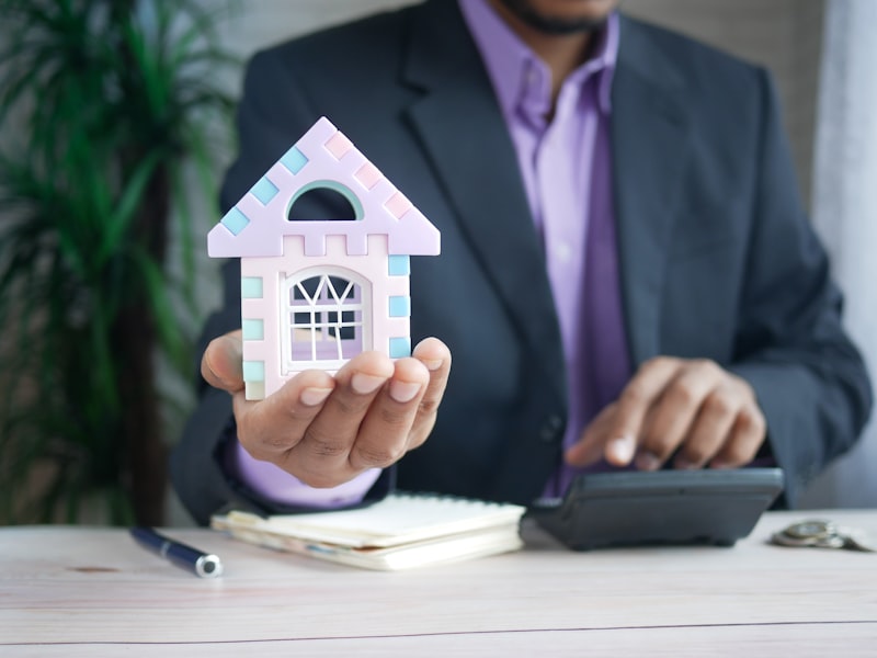 Homeowner's advisor holding a model house while working a calculator